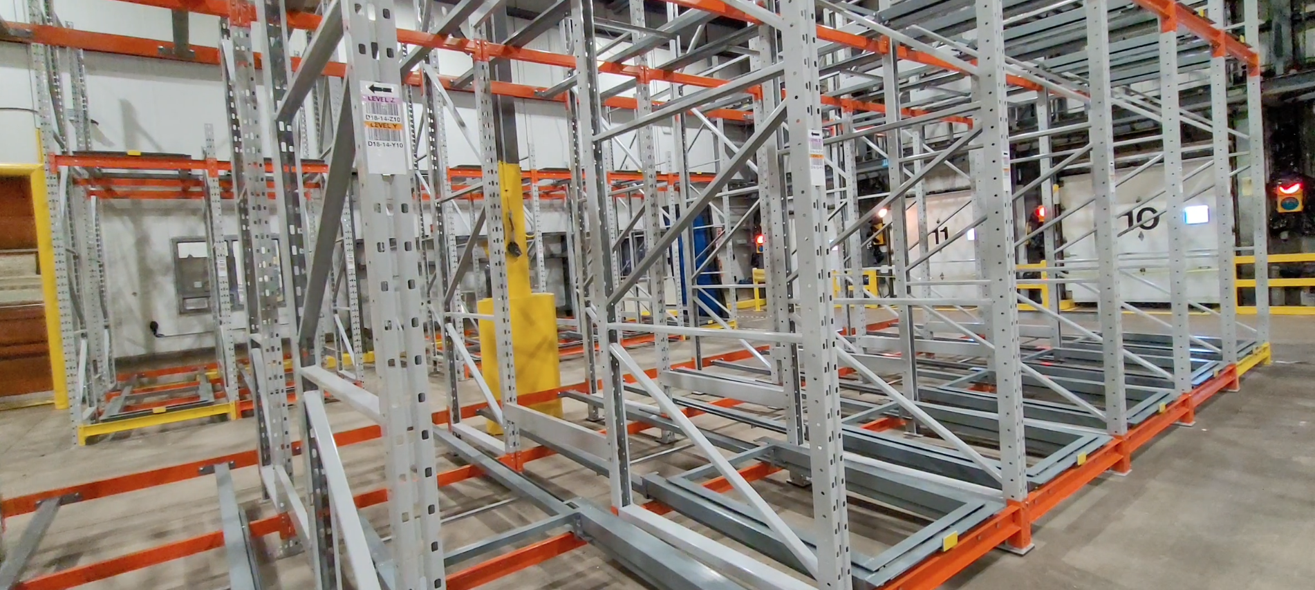 Heavy-duty push back rack structure with guide rails and nested carts for pallet storage in a warehouse.