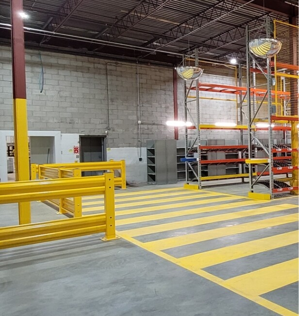 Heavy-duty industrial guardrail system protecting a conveyor line in a warehouse environment