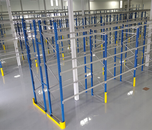 Empty drive-in pallet racking structure in a clean warehouse, designed for high-density storage with deep lane access.