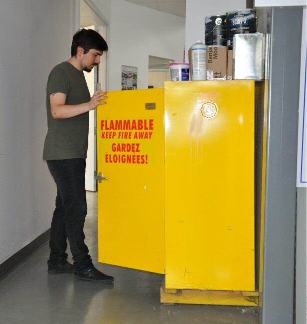 flammable cabinet in use with worker handling hazardous liquids in industrial environment