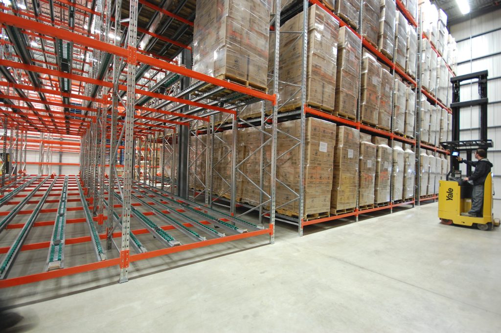 Rayonnages industriels avec cartons entreposés dans un entrepôt, illustrant une structure nécessitant une réparation ou une maintenance de rayonnage